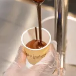 A tap is pouring liquid chocolate into a small cup at CioccolatItaliani